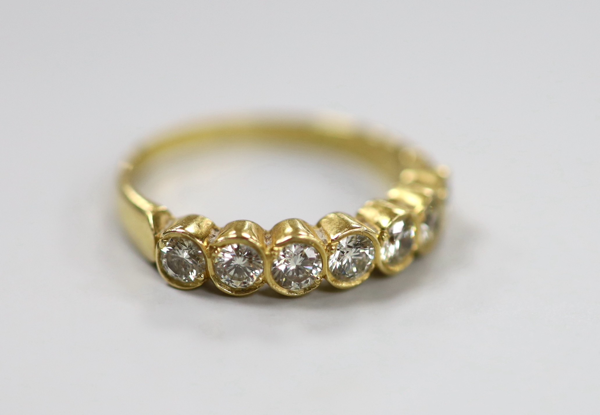 A modern 750 yellow metal and seven stone diamond set half hoop ring, size O, gross weight 3.2 grams.